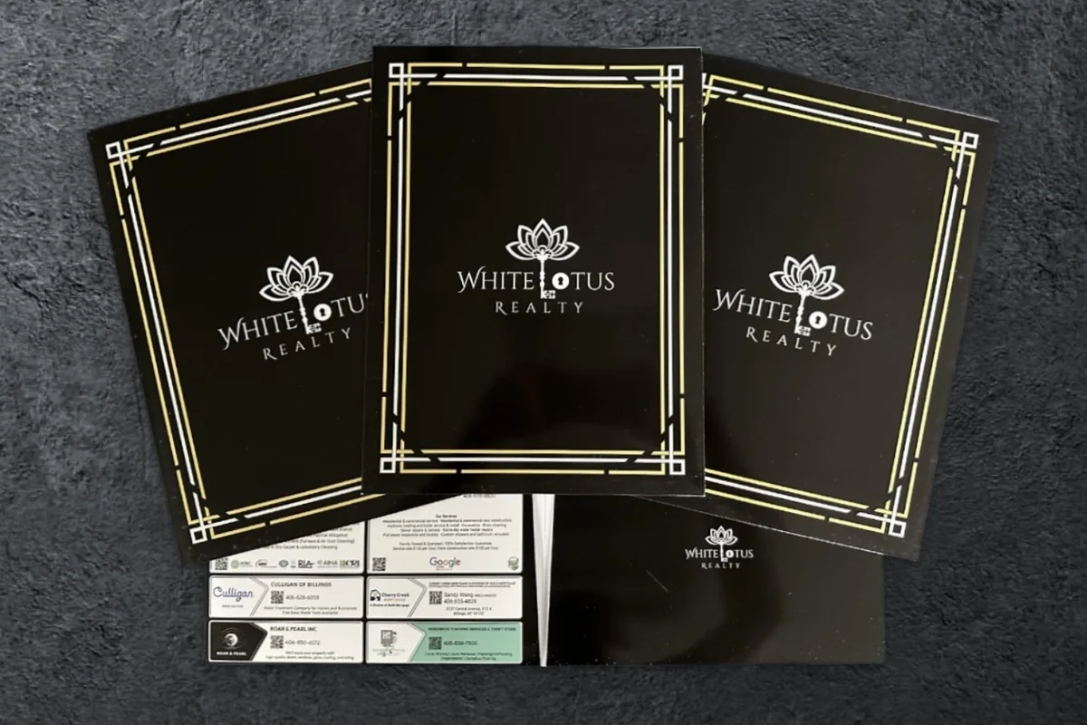 Custom black White Lotus Realty presentation folders with gold and silver borders and local vendor ads on the pocket
